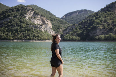 Full length of young woman standing in sea