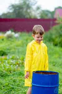 A boy in a yellow raincoat walks outside in the rain. beautiful and smiling child on the street. 