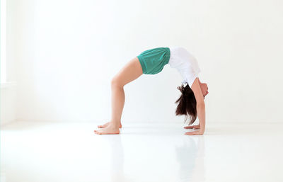 Side view of woman stretching over white background
