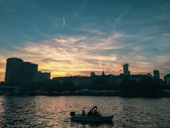 Scenic view of river by buildings against sky during sunset