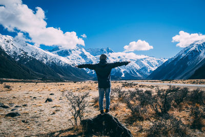 Man standing on field against snowcapped mountains