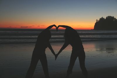 Silhouette of people on beach at sunset
