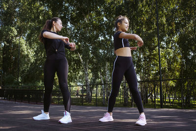 Girl in sportswear on a sunny summer day on the embankment in the park doing fitness and stretching