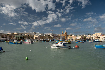 Boats moored in canal by buildings against sky