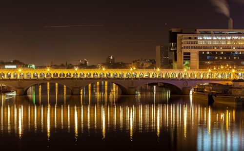 Illuminated bridge over river in city at night