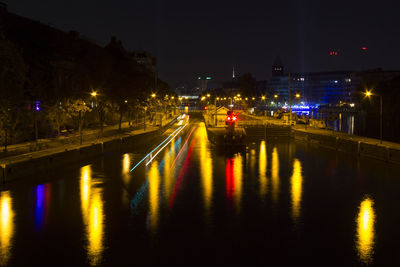 Illuminated city street by river at night