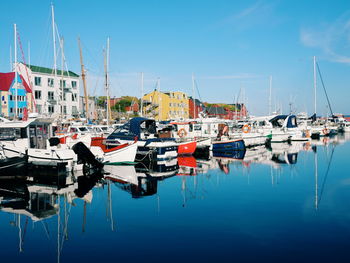 Boats moored at harbor against blue sky