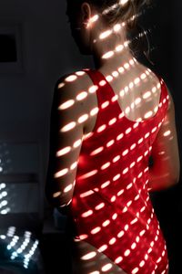 Midsection of woman standing in illuminated mirror