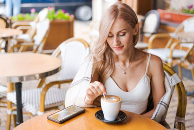Young woman while relaxing in cafe at table on street, happy caucasian woman