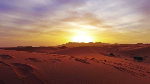 Scenic view of sand dunes against sky during sunset