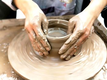 Cropped hands of person molding shape on pottery wheel