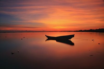 Silhouette boat on lake against sky during sunset