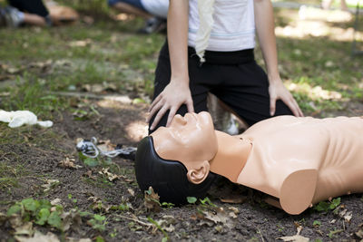 Low section of woman practicing cpr on dummy at field