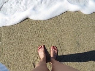 LOW SECTION OF WOMAN STANDING ON SANDY BEACH