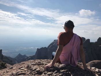 Rear view of man on rock against sky