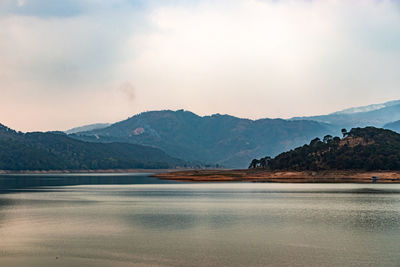 Scenic view of lake by mountains against sky