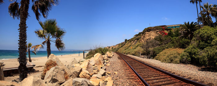 Railroad tracks on beach against clear sky