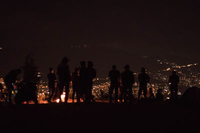 Silhouette people at illuminated park against sky at night