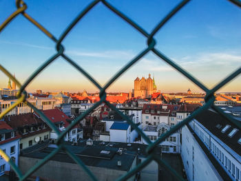 High angle view of buildings seen through chainlink fence