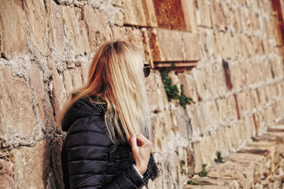 Side view of woman wearing warm clothing against wall