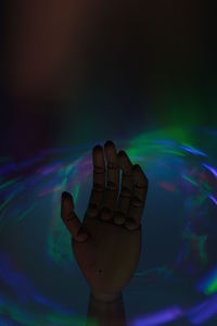 Close-up of hand holding illuminated toy in water