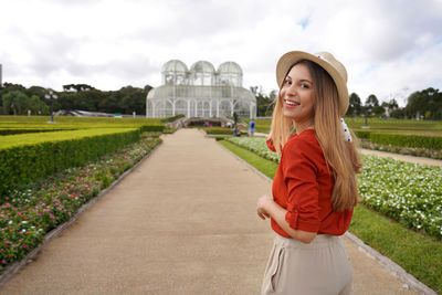 Woman with hat walking and turns to the camera in the botanical garden of curitiba, parana, brazil