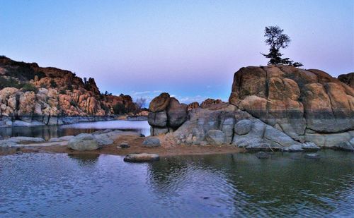 Rock formations in lake against clear sky