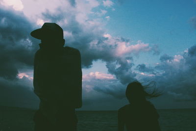 Silhouette of man standing by sea against cloudy sky