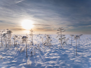 Snow covered landscape against sky during sunset