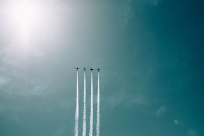 Low angle view of airplanes flying against blue sky