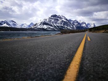 Surface level of road by snowcapped mountains against sky