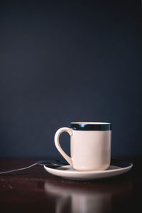 Close-up of coffee cup on table against black background