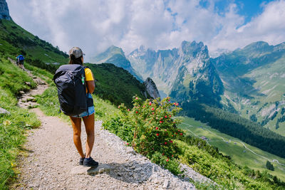 Rear view of man standing on mountain against sky