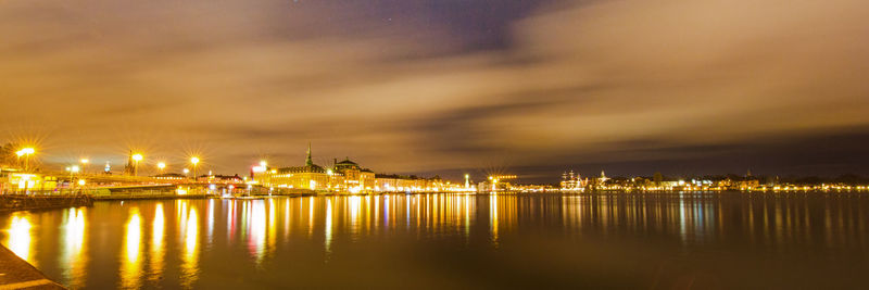 Illuminated harbor by river against sky at night