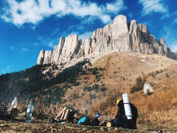 Rear view of people sitting on rock against sky