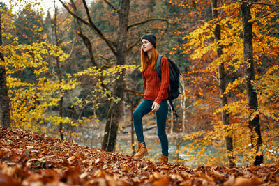 Full length of young woman with umbrella during autumn