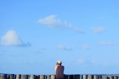 High section of man standing in front of tower against cloudy sky