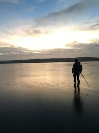 Silhouette man walking on water against sky