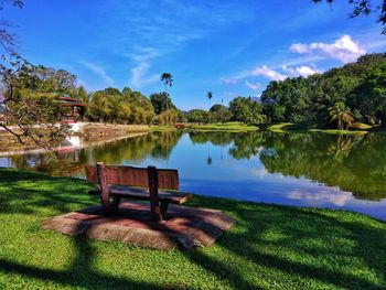 Bench by lake against sky