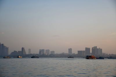 Scenic view of sea by buildings against sky during sunset