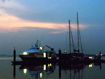 Sailboats moored at harbor during sunset