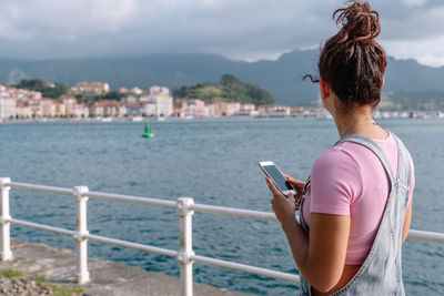 Rear view of woman photographing sea against sky