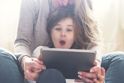 Midsection of woman using mobile phone while sitting on sofa