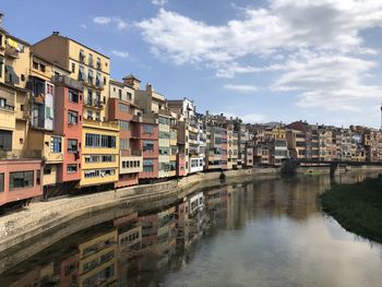 Buildings by river against sky in city