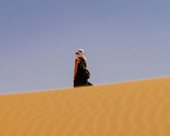 Low angle view of man standing on desert against clear sky