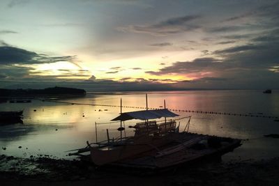 Sailboat moored on sea against sky during sunset