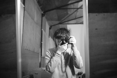 Portrait of man photographing in front of mirror