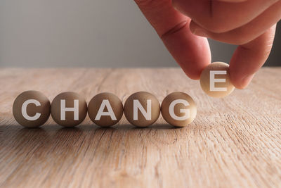 Cropped hand arranging balls with change text on wooden table