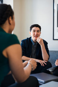 Smiling businessman listening to colleagues in meeting at office