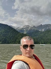 Portrait of man wearing sunglasses against lake